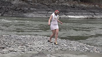 Paha Ramping Dan Bokong Montok Di Balik Gaun Mini, Gadis Rusia Ini Berjalan Santai Di Tepi Sungai.